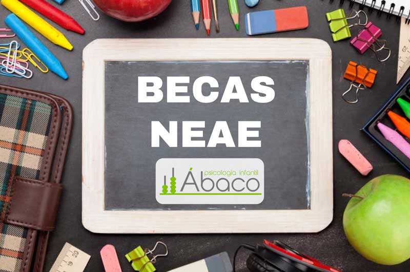 Una pequeña pizarra sobre un escritorio desordenado muestra el texto "BECAS NEAE" encima de un logo que dice "Psicología Infantil Ábaco". Los útiles escolares rodean la pizarra.