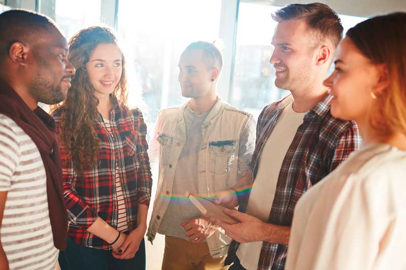 Cinco personas se encuentran en una habitación bien iluminada, enfrascadas en una conversación grupal. Una persona sostiene una tableta, posiblemente mostrando algo importante. Entre ellos se encuentra el alcalde, fácilmente reconocible y profundamente implicado en la discusión.